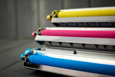 Gri ahşap arka planda cyan, morumsu ve sarı renkli lazer yazıcının Toner yenisi