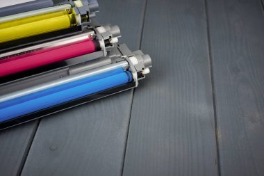 Three used toner cartridges in a color laser printer on gray wooden background for recycling clipart
