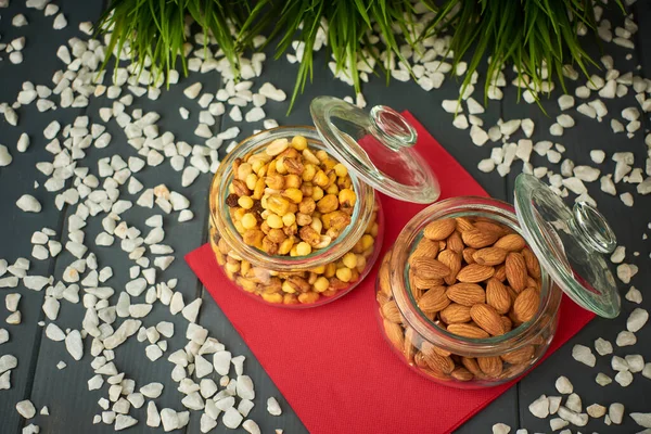 Almonds and assorted nuts such as chickpeas, corn and raisins, in glass jars for tasting at a party.