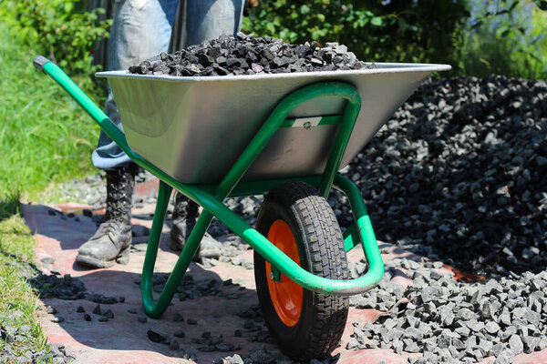 Полная тачка разбитых камней ждет своего пункта назначения под палящим солнцем.