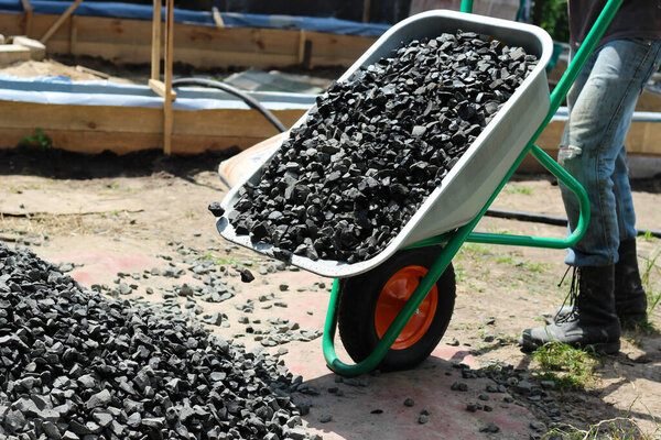 Человек двигает тачку с щебнем, как часть строительного проекта