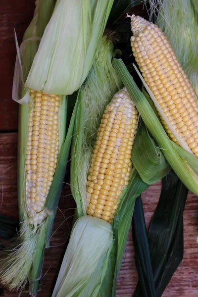 Güzel, lezzetli mısır koçanları ahşap masada yatıyor.