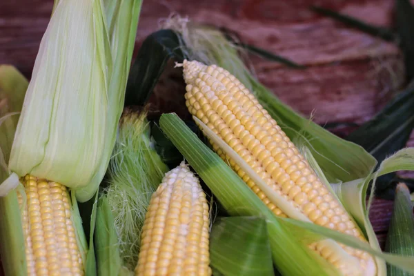 Güzel, lezzetli mısır koçanları ahşap masada yatıyor.
