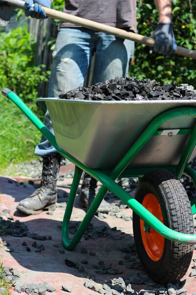 Полная тачка разбитых камней ждет своего пункта назначения под палящим солнцем.