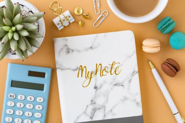 Kadın çalışma alanıyla macaroons, defter, hesap makinesi ve kahve fincanı