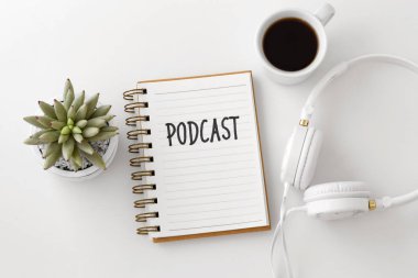 Podcast kavramı kulaklıklar, defter ve kahve fincanı beyaz masa, üstten görünüm