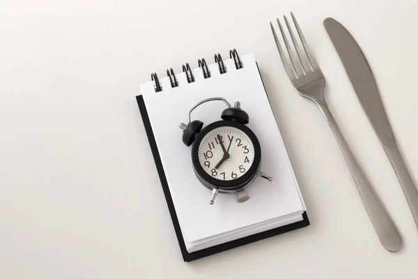 メモ帳上の時計が断続的な絶食と重量損失計画コンセプト ホワイト バック グラウンド用のナイフとフォーク — ストック写真