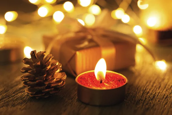 Noel mum ışığı ve bokeh ile koyu arka plan üzerinde çam kozalağı ile