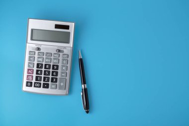 Siyah kalem ile canlı mavi arka plan, üstten görünüm alanı olan gümüş hesap makinesi