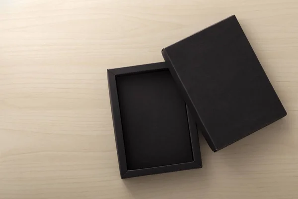 Imballaggio scatola nera su sfondo di legno — Foto Stock