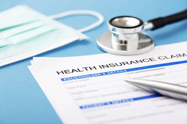 Krankenversicherungsdokument Mit Stethoskop Und Operationsmaske Auf Blauem Hintergrund — Stockfoto