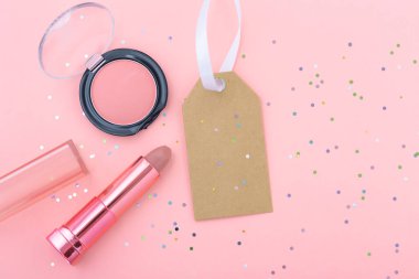 Makyaj ve makyaj malzemesi. Pastel pembe arka planda boş satış etiketi var.