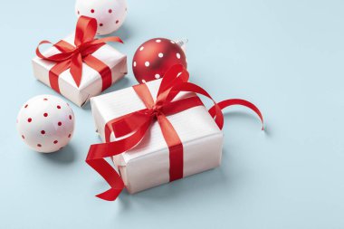 Noel tatili arka planı, hediye kutusu kırmızı yay ve açık mavi arka planda Xmas topu süslemesi, kopyalama alanı
