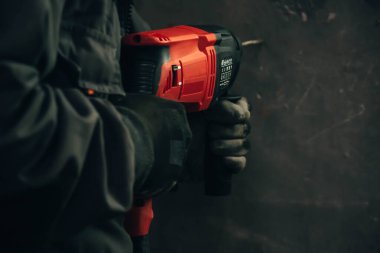 Çalışan bir adam, büyük bir matkapla bir delik açıyor.