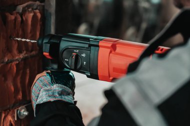 Çalışan bir adam, büyük bir matkapla bir delik açıyor.