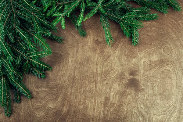 Ahşap arka planda izole edilmiş dallarla yapılmış Noel çerçevesi