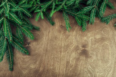 Ahşap arka planda izole edilmiş dallarla yapılmış Noel çerçevesi