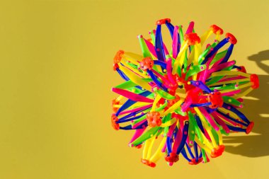 Sarı zemin üzerinde plastik çubuklardan yapılmış çok renkli ses dalgaları. Üst manzara, düz yatış. Soyut geometrik şekil, kopyalama alanı, çocuk gelişimi, çocuklar için oyunlar.