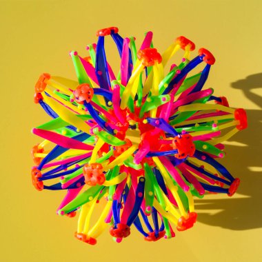 Sarı zemin üzerinde plastik çubuklardan yapılmış çok renkli ses dalgaları. kare fotoğraf. Üst manzara, düz yatış. Soyut geometrik şekiller, kopyalama alanı, çocuk gelişimi, çocuklar için oyunlar, modelleme.