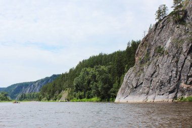 Uzağa uzanan nehrin güzel yaz manzarası kayalar ve çam ormanları, bulutlu gökyüzü. Kopya uzayı, seyahat hayali, resimli bir nehirde rafting, tekne gezisi. Rusya Ural.