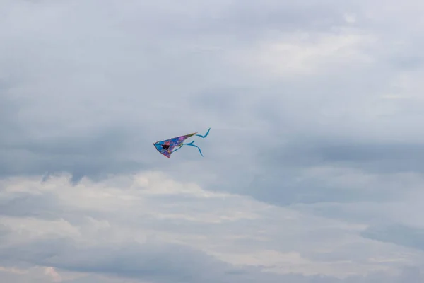 Flying kite in the blue sky. Beautiful multi-colored kite in the blue sky. Colorful baby kite flying high in the sky. Freedom to fly, dream, childrens fun, freedom, copy space. — Stock Photo, Image