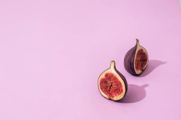 Pembe arka planda incir yarımları. Arka plan. sağlıklı yeme kavramı