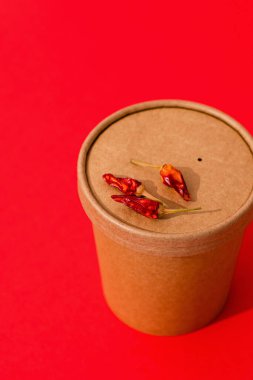 Kırmızı arka planda kırmızı biberli bir konteynıra koymak için baharatlı çorba. Paket yemek. Kargo