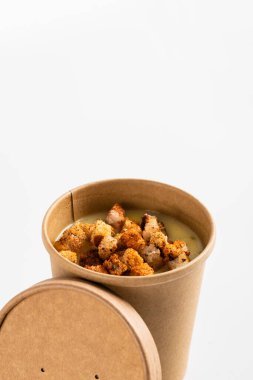 Patates kremalı çorba ve beyaz bir arka planda ekmek kızartma kabı. Sebze çorbası, yiyecek teslimatı, yakın çekim.