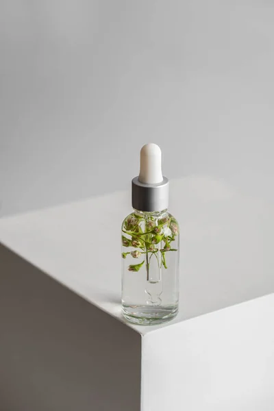 Serumlu şeffaf şişe ve açık arkaplanda cilt bakımı için pipetli çiçekler. Doğal malzemeli kozmetik ürünler. Sağlık ve güzellik kavramı. minimalizm, boşluğu kopyala