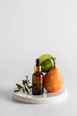 Serumla birlikte cam kahverengi bir şişe ve arka planda cilt bakımı için bir pipet. Limonlu, armutlu ve zeytinli kompozisyon. Sağlık ve güzellik kavramı. minimalizm, boşluğu kopyala