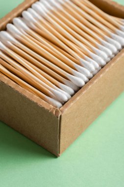 Çevresel bambu kulaklar yeşil arka plandaki bir el işi kutusuna yapışır. Yaşam tarzı konsepti. sıfır atık, plastiksiz eşyalar. Plastik kirliliğini durdurun. tekrar kullan, azalt, geri dönüştür, reddet