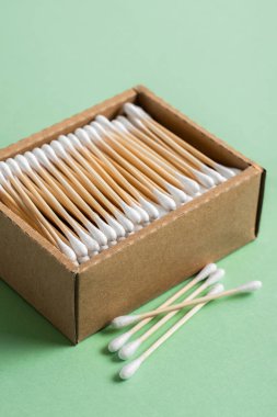 Çevresel bambu kulaklar yeşil arka plandaki bir el işi kutusuna yapışır. Yaşam tarzı konsepti. sıfır atık, plastiksiz eşyalar. Plastik kirliliğini durdurun. tekrar kullan, azalt, geri dönüştür, reddet