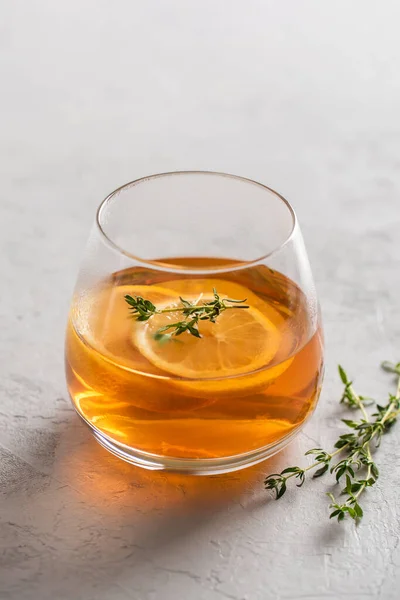 Warme thee in een glas met citroen en tijm op een grijze achtergrond met kopieerruimte, zijlicht. Herfst en winter traditionele dranken. — Stockfoto
