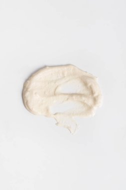 Beyaz arka planda beyaz kozmetik krem lekeleri. Cilt bakım losyonu serum doku örneği. Bir güzellik ürünü örneğine yakın çekim.
