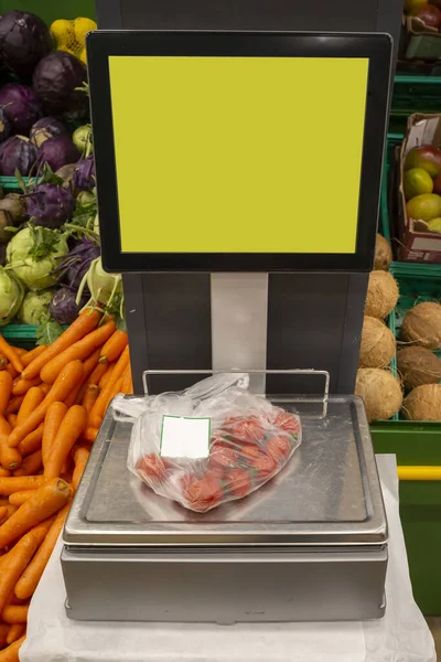 weighing of vegetable on electronic scales in supermarket
