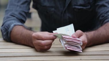Parayı ahşap masada tutan el.,