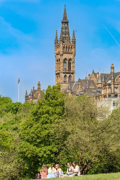 苏格兰格拉斯哥 2018年5月19日 春末的 Kelvingrove Kelvingrove 公园享受阳光明媚的春日的学生 2018年5月19日在苏格兰格拉斯哥的格拉斯哥大学大楼 图库照片