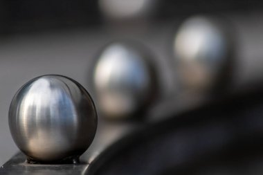 Matt steel balls in a row as decorative and ornamental balustrade and futuristic fence design with a lot of copy space, a selective focus and a blurred background for metal industry metal architecture clipart