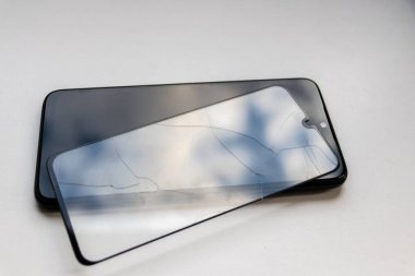 Siyah bir akıllı telefondaki kırık koruyucu kalkan, cep telefonlarının zarar görmemesi için güvenlik önlemi ve kırılmaz cihaz koruyucularını gösteriyor.
