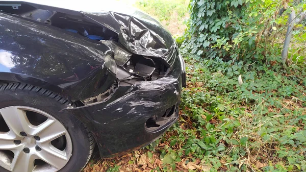 Crashed car with a destroyed front and car engine hood shows misfortune and the need for car insurance to avoid financial total loss and collision safety or repair after collision and emergency