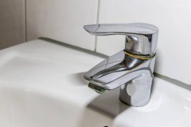 Duş veya musluk lavabosunda paslanmaz krom kaplı ekipmanlarla eski fosil banyo tesisatları ve fosil hijyeniği, krom anahtara damlayan su nedeniyle onarım onarımı gösteriyor.