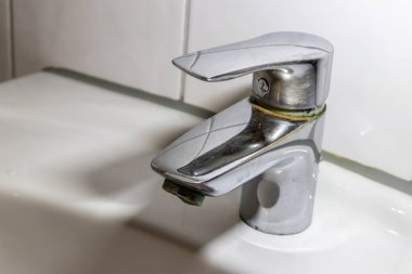 Duş veya musluk lavabosunda paslanmaz krom kaplı ekipmanlarla eski fosil banyo tesisatları ve fosil hijyeniği, krom anahtara damlayan su nedeniyle onarım onarımı gösteriyor.