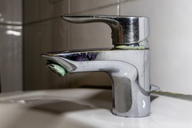 Duş veya musluk lavabosunda paslanmaz krom kaplı ekipmanlarla eski fosil banyo tesisatları ve fosil hijyeniği, krom anahtara damlayan su nedeniyle onarım onarımı gösteriyor.