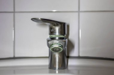 Duş veya musluk lavabosunda paslanmaz krom kaplı ekipmanlarla eski fosil banyo tesisatları ve fosil hijyeniği, krom anahtara damlayan su nedeniyle onarım onarımı gösteriyor.