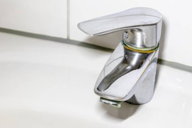 Duş veya musluk lavabosunda paslanmaz krom kaplı ekipmanlarla eski fosil banyo tesisatları ve fosil hijyeniği, krom anahtara damlayan su nedeniyle onarım onarımı gösteriyor.