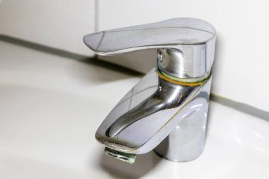 Duş veya musluk lavabosunda paslanmaz krom kaplı ekipmanlarla eski fosil banyo tesisatları ve fosil hijyeniği, krom anahtara damlayan su nedeniyle onarım onarımı gösteriyor.