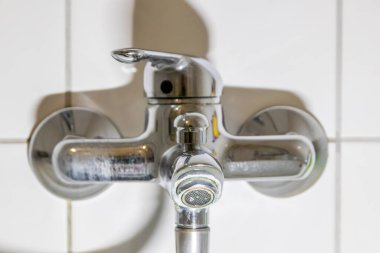 Duş veya musluk lavabosunda paslanmaz krom kaplı ekipmanlarla eski fosil banyo tesisatları ve fosil hijyeniği, krom anahtara damlayan su nedeniyle onarım onarımı gösteriyor.