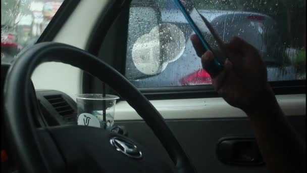 男は雨が降ったときに携帯電話で遊んでいる間 車を運転しています — ストック動画