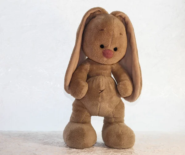 A fluffy hare on a light background. Toy rabbit.