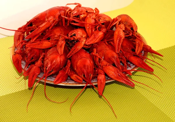 Boiled crawfish on a plate on a green background.